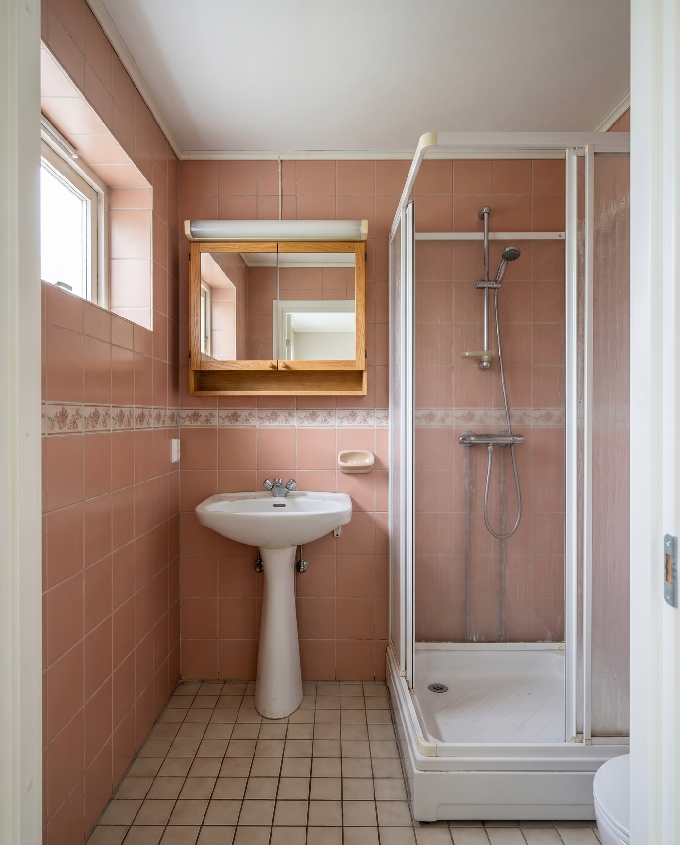 Dated 1990s bathroom before renovation, with old pink tiles and fittings